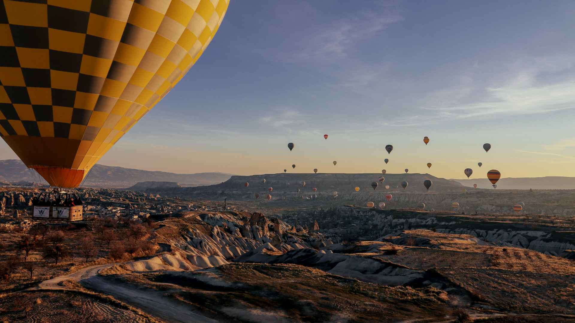 Inspiring view of a large hot air balloon in the foreground, dozens of hot air balloons in the background, floating above majestic scenery